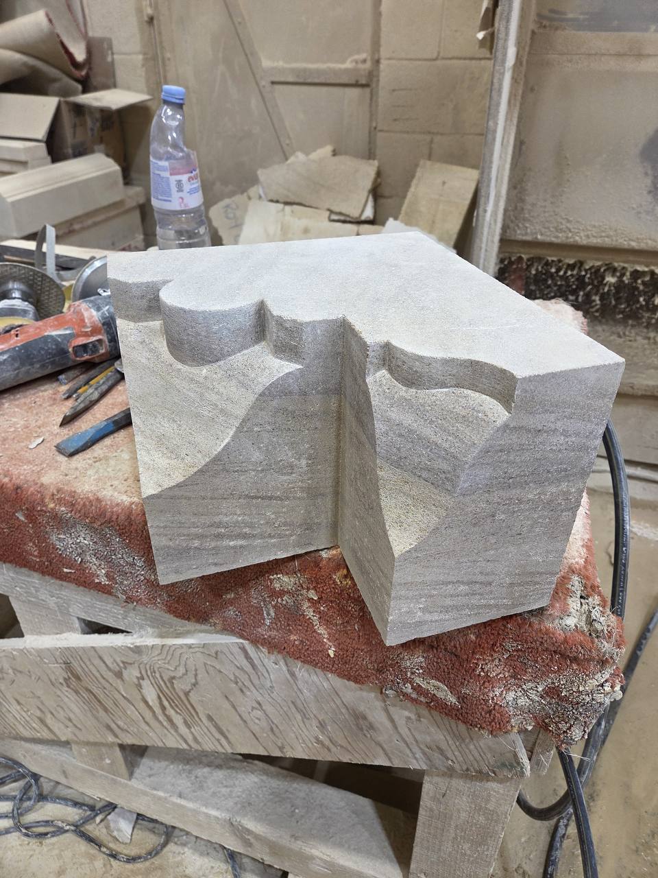 Carved sandstone pier cap with scalloped mouldings worked on each face, part-finished on the banker bench.
