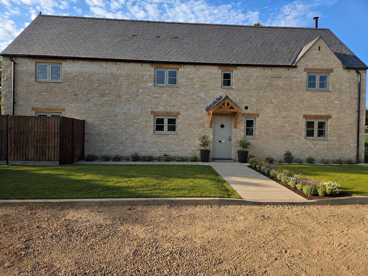 Front elevation of a new build limestone house at Easton on the Hill, with cropped walling stone, oak lintels and an oak porch canopy.