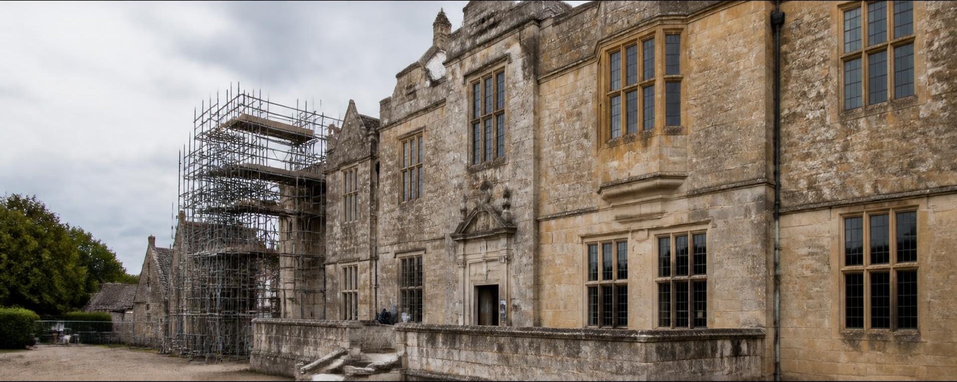 Listed limestone manor elevation under conservation, with traditional scaffolding and freshly repointed lime mortar joints