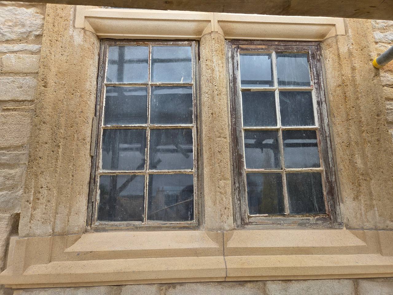 Restored stone mullion window on a historic building, with new dressed limestone jambs, mullion, lintel and moulded cill set into the existing rubble walling